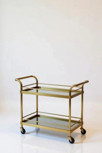 French Empire gold brass bar trolley with two glass shelves, wheeled design, ornate rococo frame, and regal antique gold finish