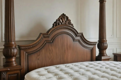 Close-up of a hand-carved antique style wooden headboard with intricate floral scrollwork and crown molding.