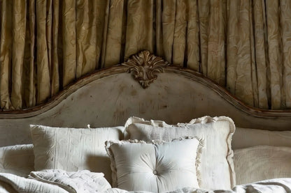 Carved wooden headboard detail of antique white four poster canopy bed in French Provincial style