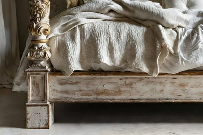 Distressed antique white wooden footboard of luxury four poster canopy bed in French Provincial style