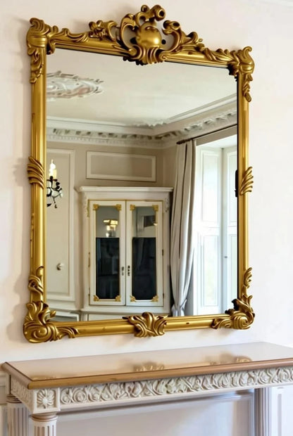 Grand arched gold leaf mirror in French Empire Rococo style with ornate carved frame, placed above matching mahogany console table