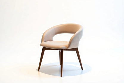 Contemporary beige upholstered dining armchair with curved barrel back, padded seat, and tapered walnut legs, mid-century modern style