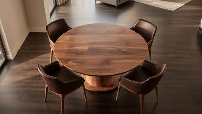 Overhead view of modern walnut round dining table with rich grain top and wide pedestal, encircled by four luxurious brown leather armchairs in a sophisticated interior