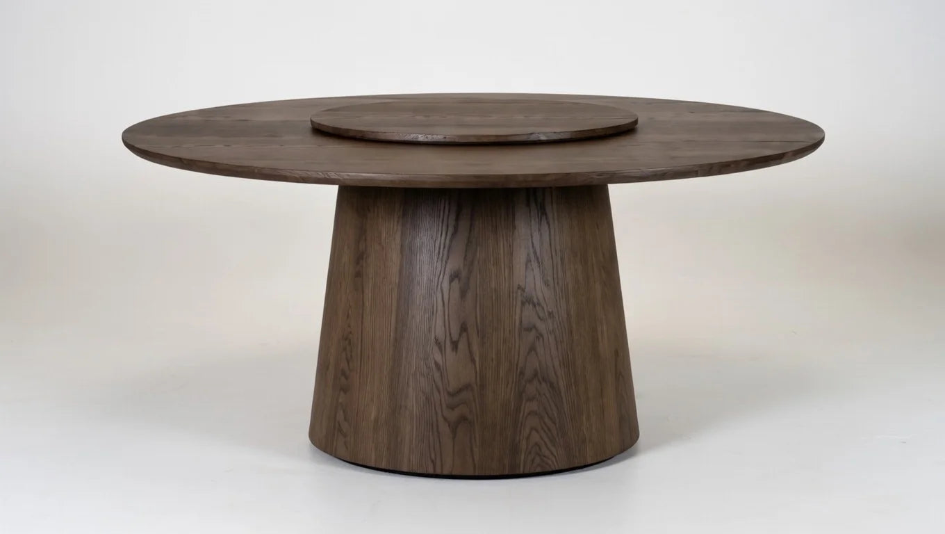 Large round solid walnut dining table with integrated lazy Susan rotating center and tapered pedestal base, natural wood grain detail, minimalist luxury style