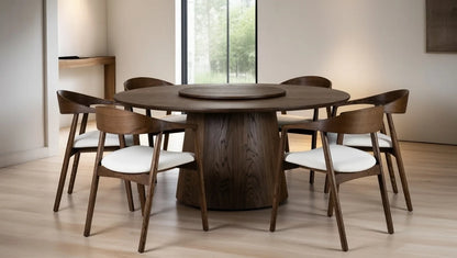 Modern round walnut dining table with lazy Susan rotating top, pedestal base, and six curved arm walnut chairs with white cushions in contemporary dining room