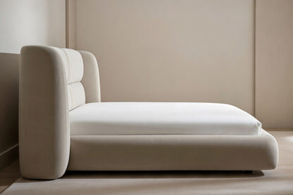 Side view of modern upholstered shelter platform bed showing low profile base and curved wingback headboard in neutral fabric