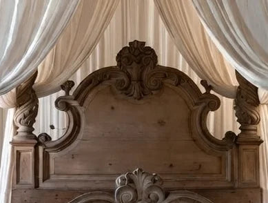 Detailed view of the ornate Rococo headboard carving and spiral-turned posts on a natural oak Provincial canopy bed.