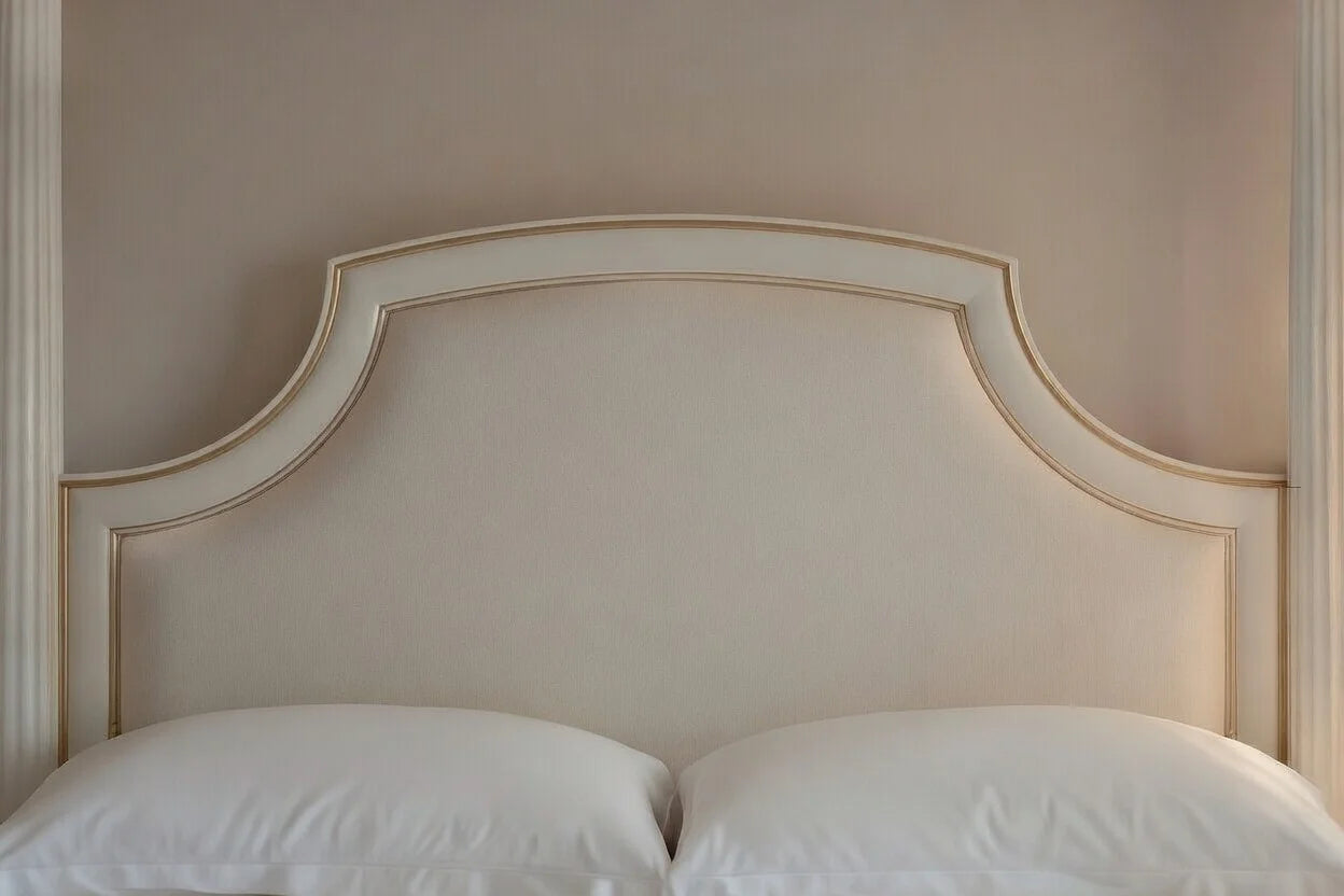 Close-up of a hand-carved solid teak headboard with champagne gold accents for a luxury round bed.