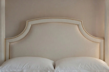 Close-up of a hand-carved solid teak headboard with champagne gold accents for a luxury round bed.