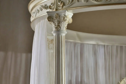 Close-up of an ornate canopy bed with white curtains.