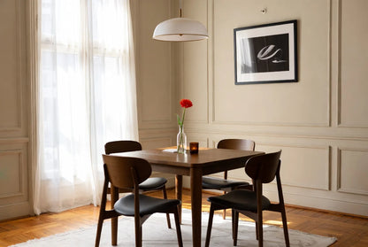 Square solid walnut dining table 4 seater with mid-century modern tapered legs, paired with 4 dark upholstered chairs in minimalist Danish-inspired room
