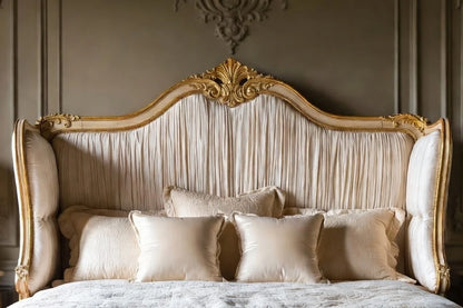 Close-up of tufted upholstered wingback headboard with carved wood trim on French style panel bed